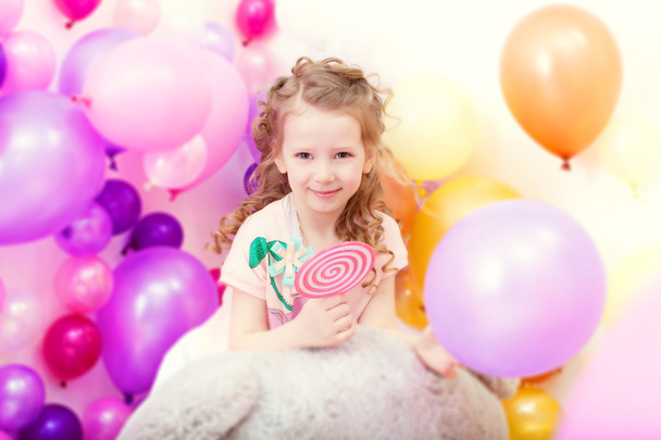 Adorable curly girl posing on balloons backdrop - Fotoğraf, Görsel