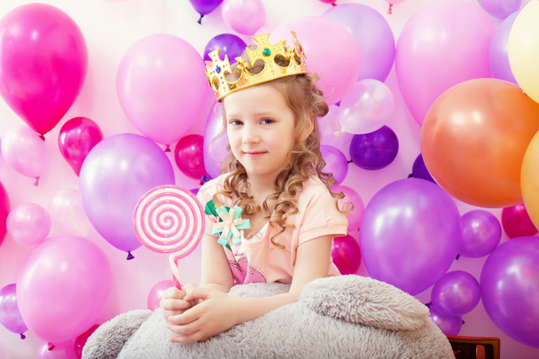 Lovely curly girl posing in crown with lollipop - Fotoğraf, Görsel