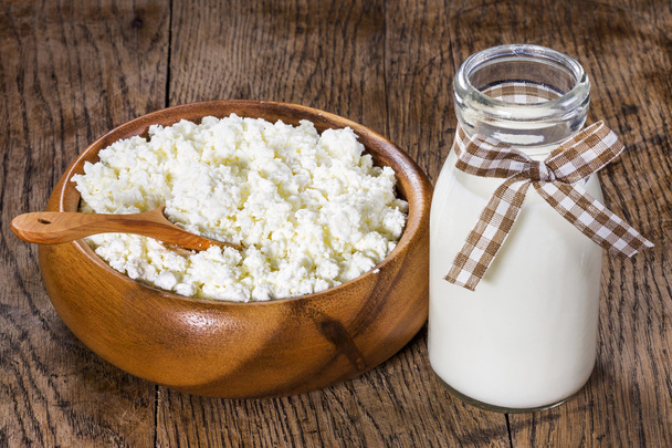 cottage cheese in a wooden plate with milk in a glass bottles  - Zdjęcie, obraz