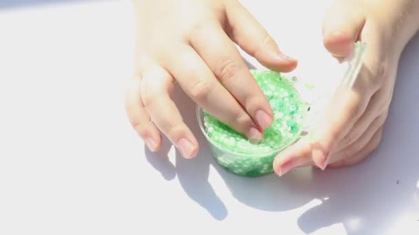 as mãos de uma menina brincando com um lodo verde brilhante puxa-lo para fora de um recipiente, close-up - Filmagem, Vídeo