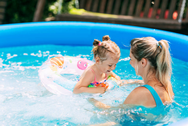 Iloinen terve äiti ja tytär leikkivät uima-altaassa. Yhteinen aika, kesäaika, loma - Valokuva, kuva