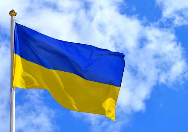 The national yellow and blue flag of Ukraine over the sky and clouds - Photo, Image