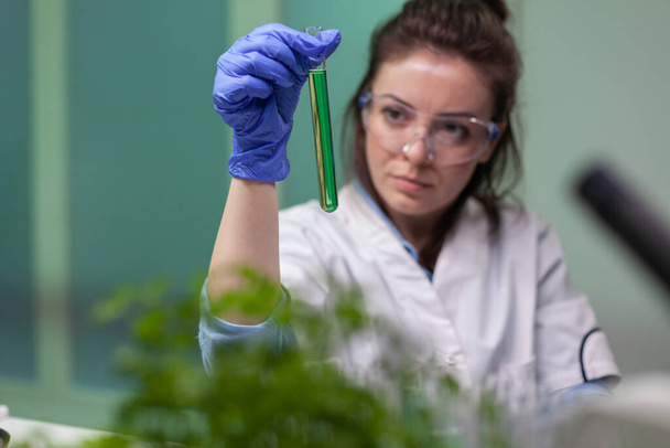 Женщина-химик держит пробирку с жидкостью ДНК - Фото, изображение