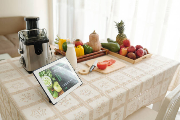Tablet computer with green smoothie receta en la mesa de la cocina con frutas frescas, verduras y licuadora - Foto, Imagen