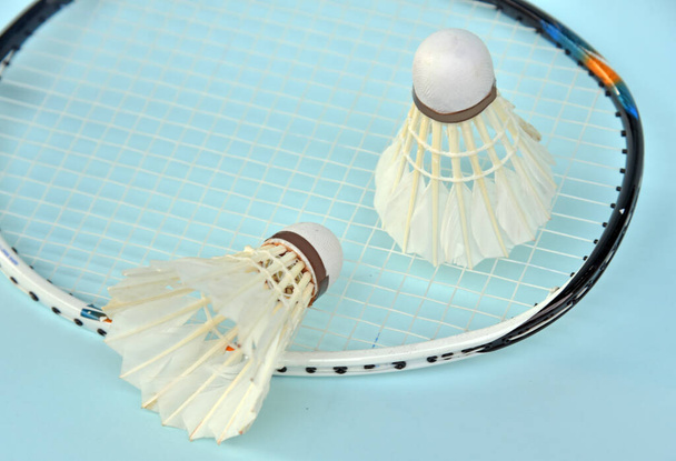 Badminton shuttelcock with racket as a background isolated on light blue color - Photo, Image