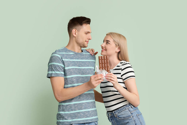 Young couple with tasty chocolate on color background - Foto, imagen
