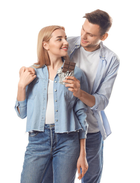 Young couple eating tasty chocolate on white background - Foto, Imagen