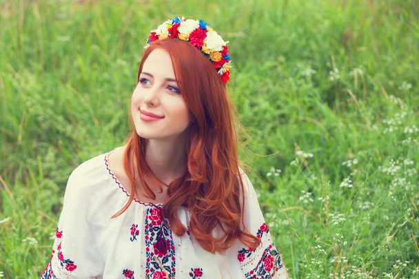 Redhead girl in nationac ukrainian clothes on the green grass. - Photo, Image