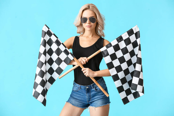 Hermosa mujer joven con banderas de carreras en el fondo de color - Foto, Imagen