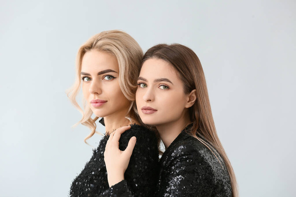 Beautiful young sisters on light background - Photo, Image