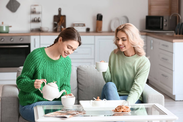Beautiful young sisters drinking tea at home - Фото, изображение