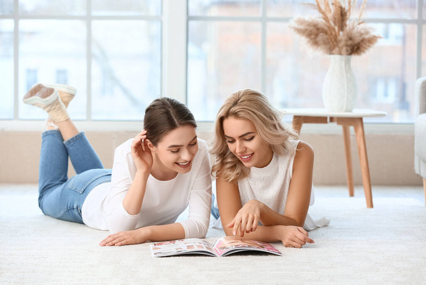 Mooie jonge zusjes die thuis tijdschrift lezen - Foto, afbeelding