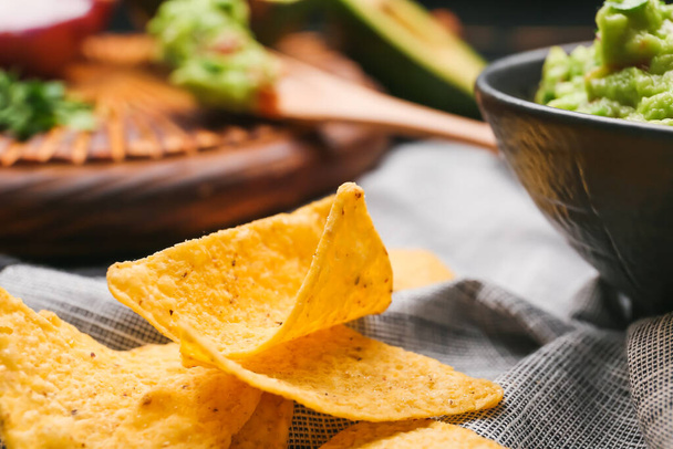 Bowl with tasty guacamole and nachos on table, closeup - 写真・画像