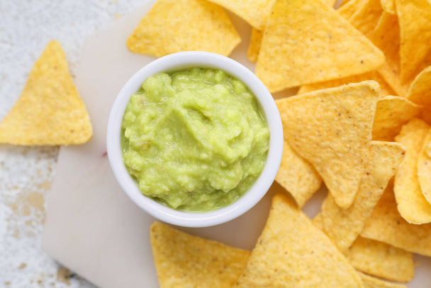 Bowl with tasty guacamole and nachos on light background, closeup - Foto, Imagen
