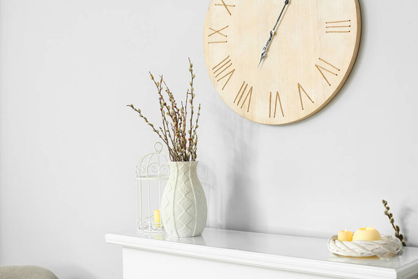 Váza s vrbovými větvemi a svíčkami na krbu u bílé stěny - Fotografie, Obrázek
