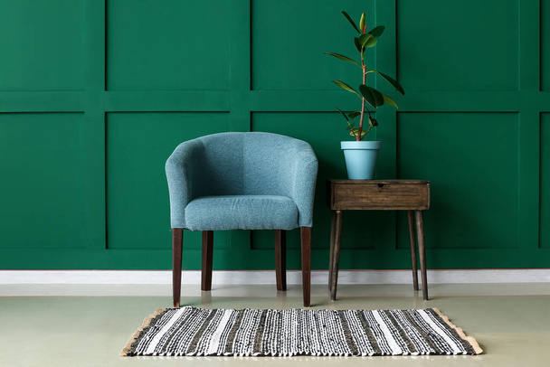 Stijlvolle fauteuil en tafel met kamerplant in de buurt van kleur muur - Foto, afbeelding
