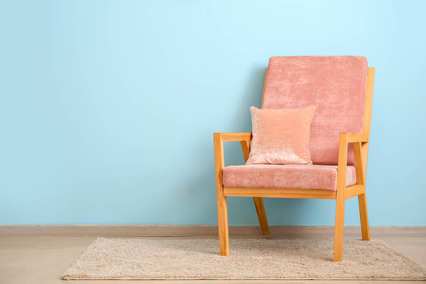 Κομψή πολυθρόνα με μαξιλάρι κοντά σε χρωματιστό τοίχο - Φωτογραφία, εικόνα