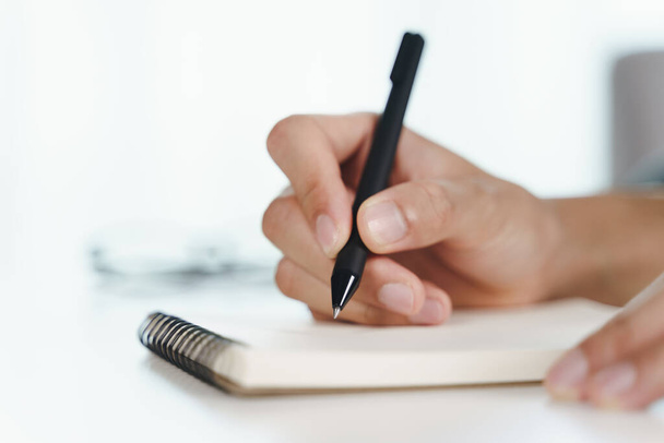 Close up de jovem em mãos de pano casuais escrevendo no bloco de notas, notebook usando caneta esferográfica na mesa. - Foto, Imagem