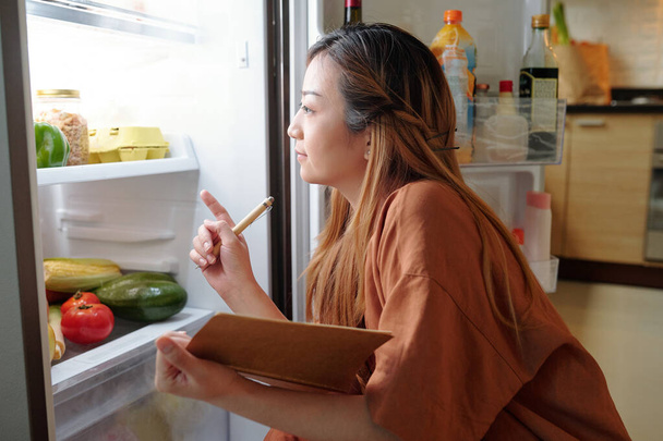 Жінка перевіряє товари в холодильнику - Фото, зображення