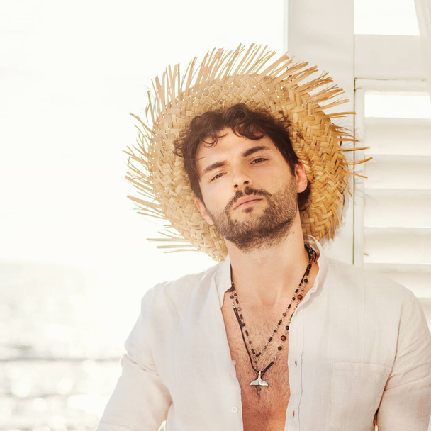 Sexy man model portrait dressed in straw hat, and white shirt, outdoor photo - 写真・画像