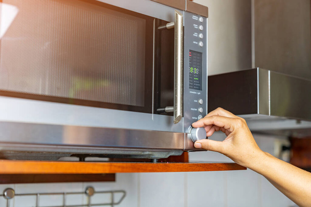 Horno temporizador de ajuste de mujer para cocinar alimentos en microondas. Concepto de cocina rápida. - Foto, imagen