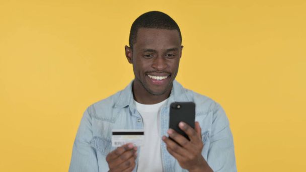 Online nakupování na Smartphone od Young African Man, žluté pozadí  - Fotografie, Obrázek