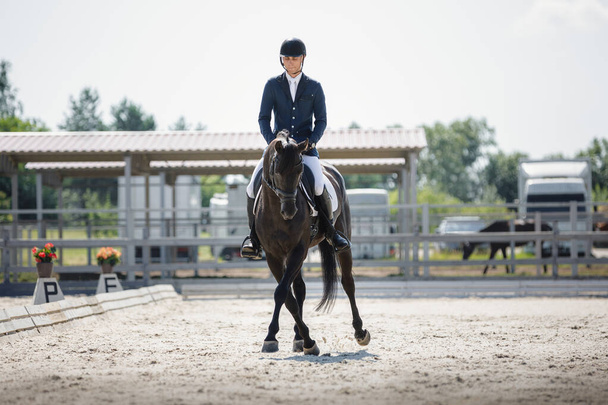 portrait of man rider and black stallion eventing horse trotting leg-yield during equestrian dressage competition in summer - Φωτογραφία, εικόνα