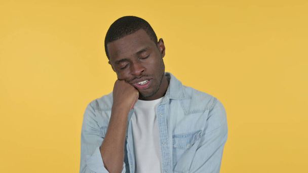 Спящий молодой афроамериканец на желтом фоне  - Фото, изображение