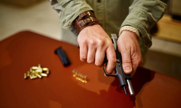 Man loads the gun with bullets in gun store. Weapon shop interior, ammo and ammunition assortment, firearms choice, shooting hobby and lifestyle, self protection - Foto, Imagen