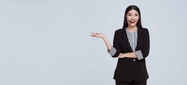 Smiling Asian businesswoman customer support phone operator isolated over gray background. call center and customer service concept. - Zdjęcie, obraz