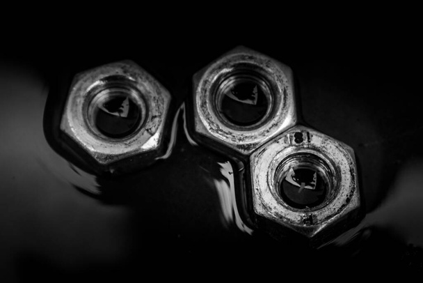 Close up of set of rusty screw-nuts on a black background with copy space - Fotografie, Obrázek