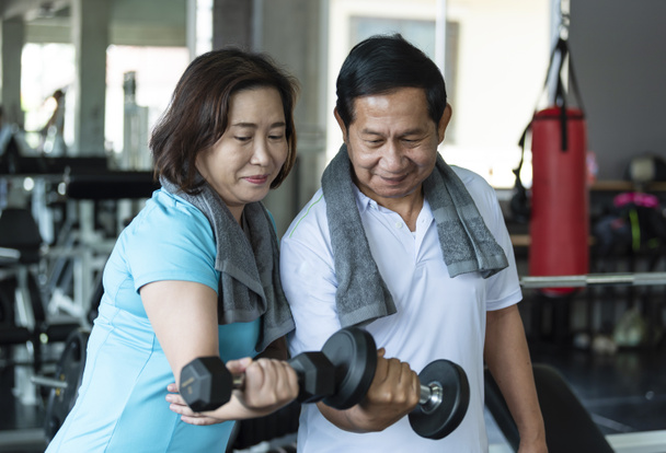 Azjatycki senior mężczyzna i kobieta ćwiczą podnoszenie hantli w siłowni. w podeszłym wieku zdrowy styl życia - Zdjęcie, obraz