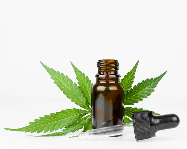 bottiglia con olio di canapa e foglie di cannabis su uno sfondo leggero - Foto, immagini