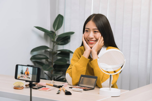 Aziatische tiener meisjes doen make-up vlogs en met behulp van een video mobiele camera om vlogs op te nemen en online te publiceren thuis. - Foto, afbeelding