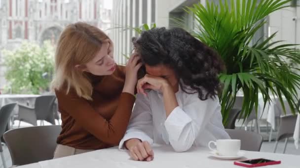Mujer joven consuela a su amiga llorando mientras está sentada en un café de la calle. Amistad femenina. Una chica llora, la otra la consuela. - Imágenes, Vídeo