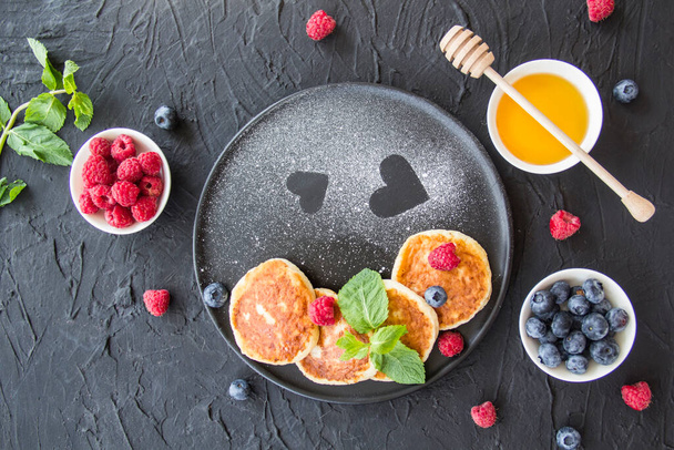 A healthy breakfast of cheese pancakes, berries, and honey. Creative atmospheric decoration - Foto, Imagen
