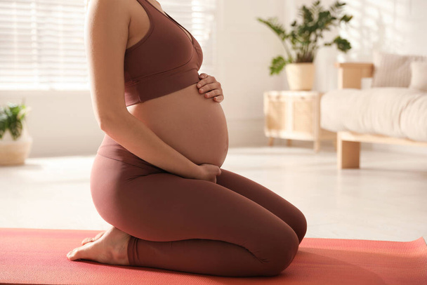 Young pregnant woman practicing yoga at home, closeup - Фото, изображение