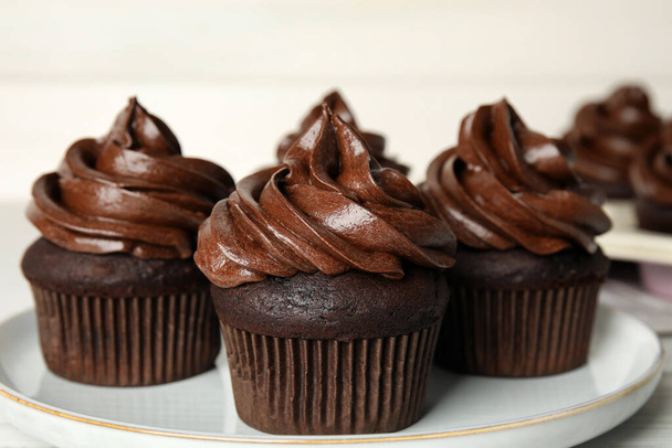 Delicious chocolate cupcakes with cream on plate, closeup - Photo, image