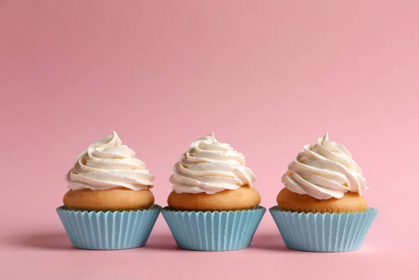Delicious cupcakes decorated with cream on pink background - Фото, зображення