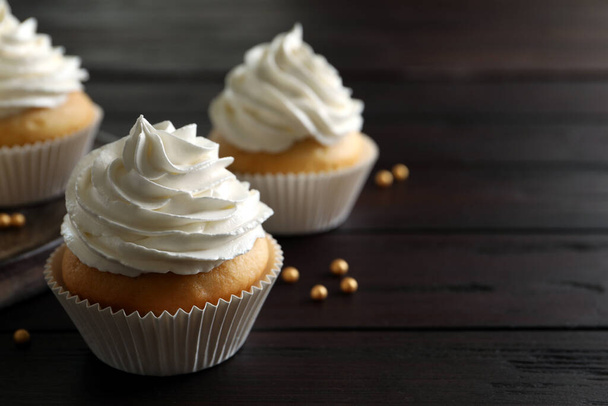 Delicious cupcakes with white cream on wooden table, closeup. Space for text - Foto, Imagem