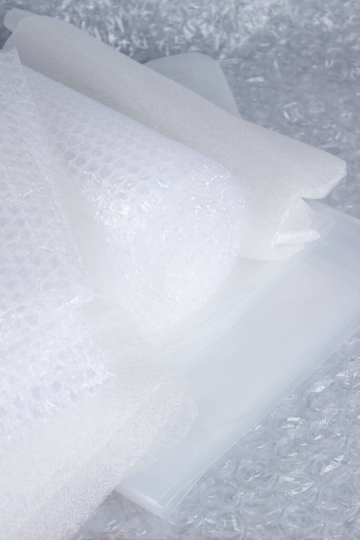 Set of plastic packaging materials - plastic stretch film rolls, foamed polyethylen sheets and rolls, different packaging films, small and large bubblewrap rolls. Selective focus, vertical image - Photo, image