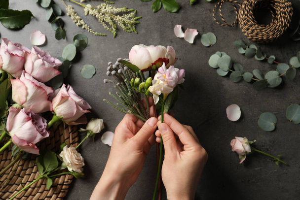 Florist creating beautiful bouquet at black table, top view - Photo, image