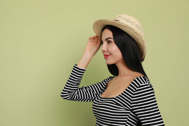 Beautiful young woman with straw hat on light green background. Space for text - Fotoğraf, Görsel