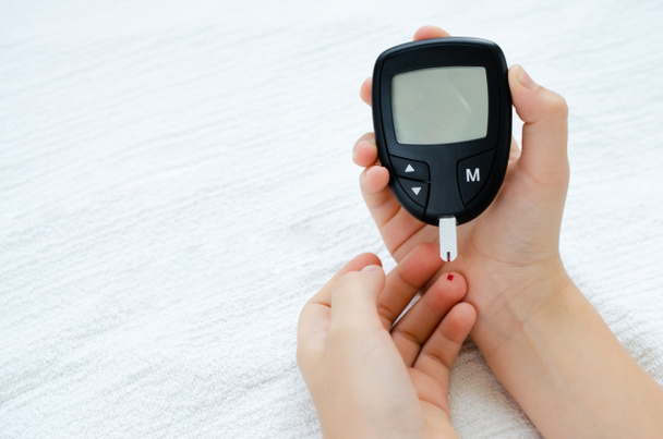 Тест на діабет. Дитячі руки перевіряють рівень цукру в крові за лічильником глюкози
. - Фото, зображення