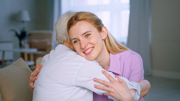 Hugging elderly mother and smiling daughter in the apartment - Photo, Image