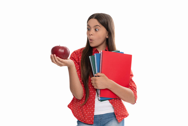 здивована дівчина з блокнотом. повернутися до школи. дитина з яблуком готова вчитися. здорове дитинство
. - Фото, зображення