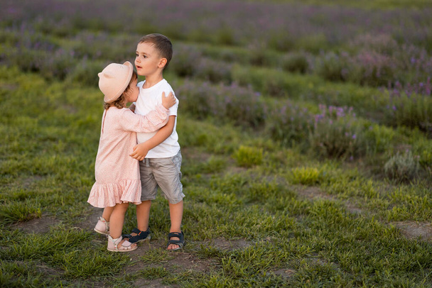 kleine jongen en meisje hebben plezier in een veld van bloemen - Foto, afbeelding