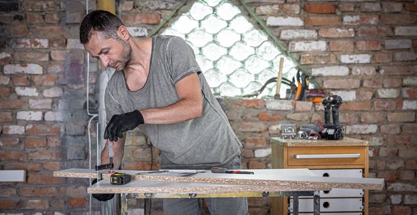 Stolarz wykonujący prace stolarskie przy użyciu narzędzia mocującego w swoim warsztacie. - Zdjęcie, obraz