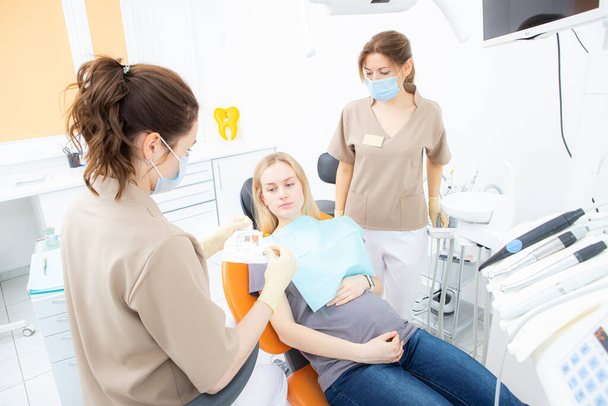 έγκυος στο γραφείο οδοντιάτρων, εξέταση και οδοντιατρική περίθαλψη εγκύων γυναικών. - Φωτογραφία, εικόνα