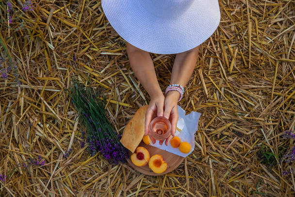 Eine Frau hält Wein in Gläsern. Picknick im Lavendelfeld. Selektiver Fokus. Natur. - Foto, Bild